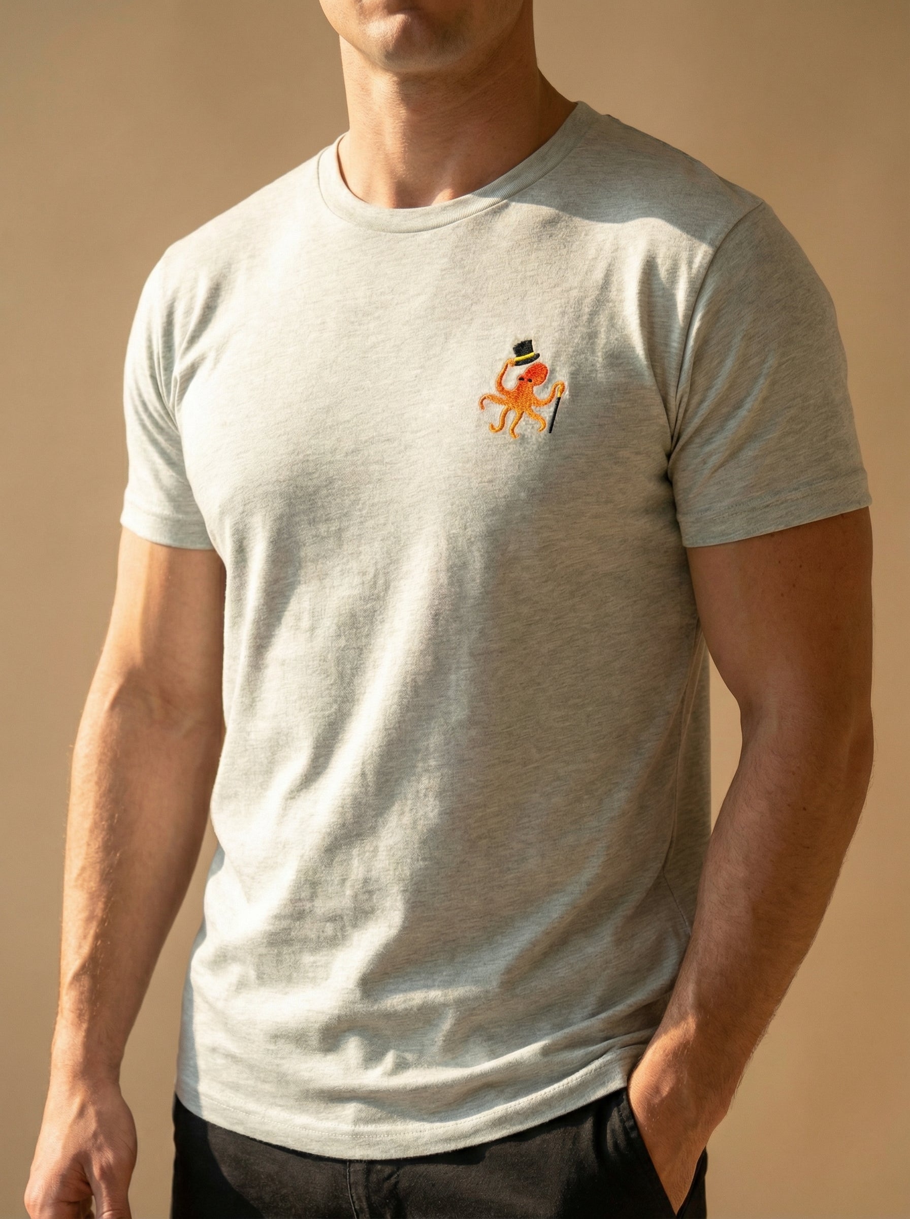 Person wearing a light gray t-shirt with a small logo on a beige background