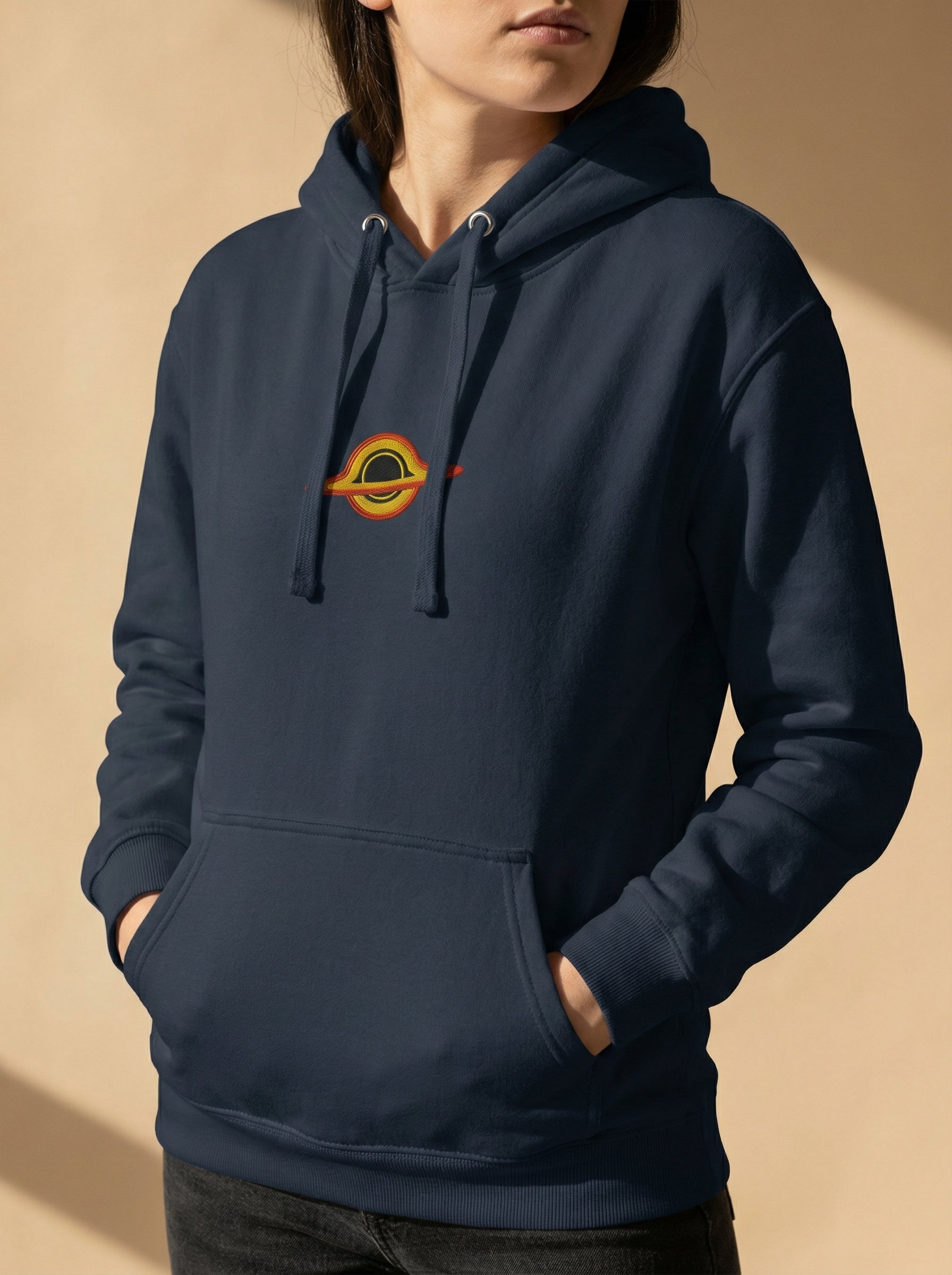 Person wearing a navy blue hoodie with a logo on a beige background