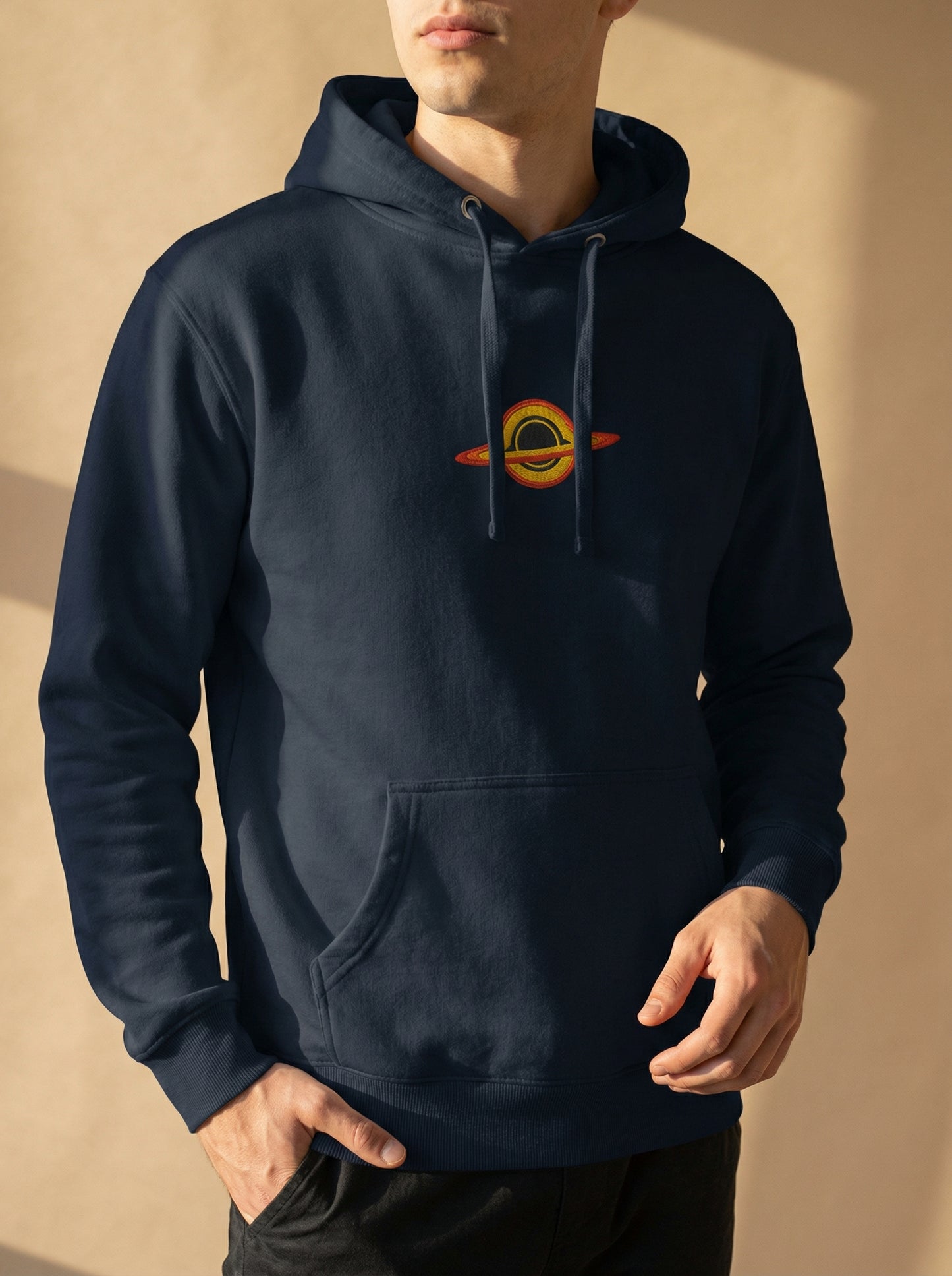Person wearing a navy blue hoodie with a logo on a beige background