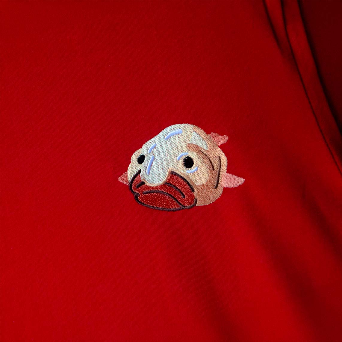 Embroidered fish design on a red fabric background