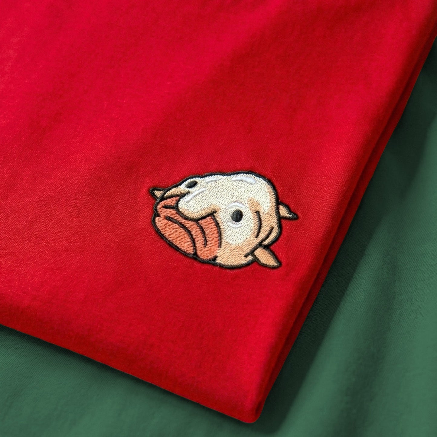 Red fabric with a cartoon duck face embroidery on a green background