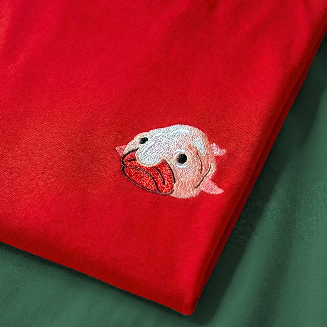 Red fabric with a pink and white embroidered design on a green background