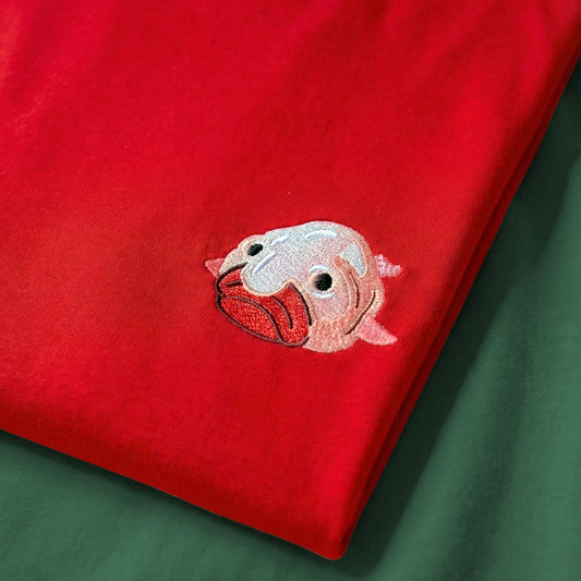 Red fabric with a pink and white embroidered design on a green background
