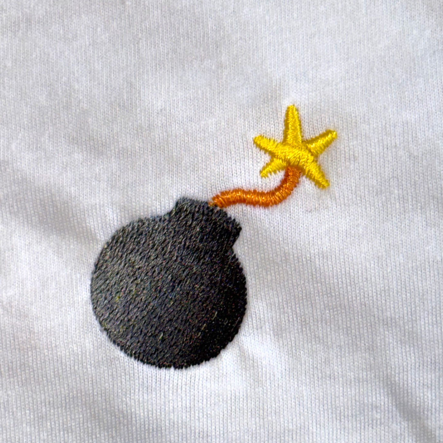 Embroidered design of a bomb with a star on a white background