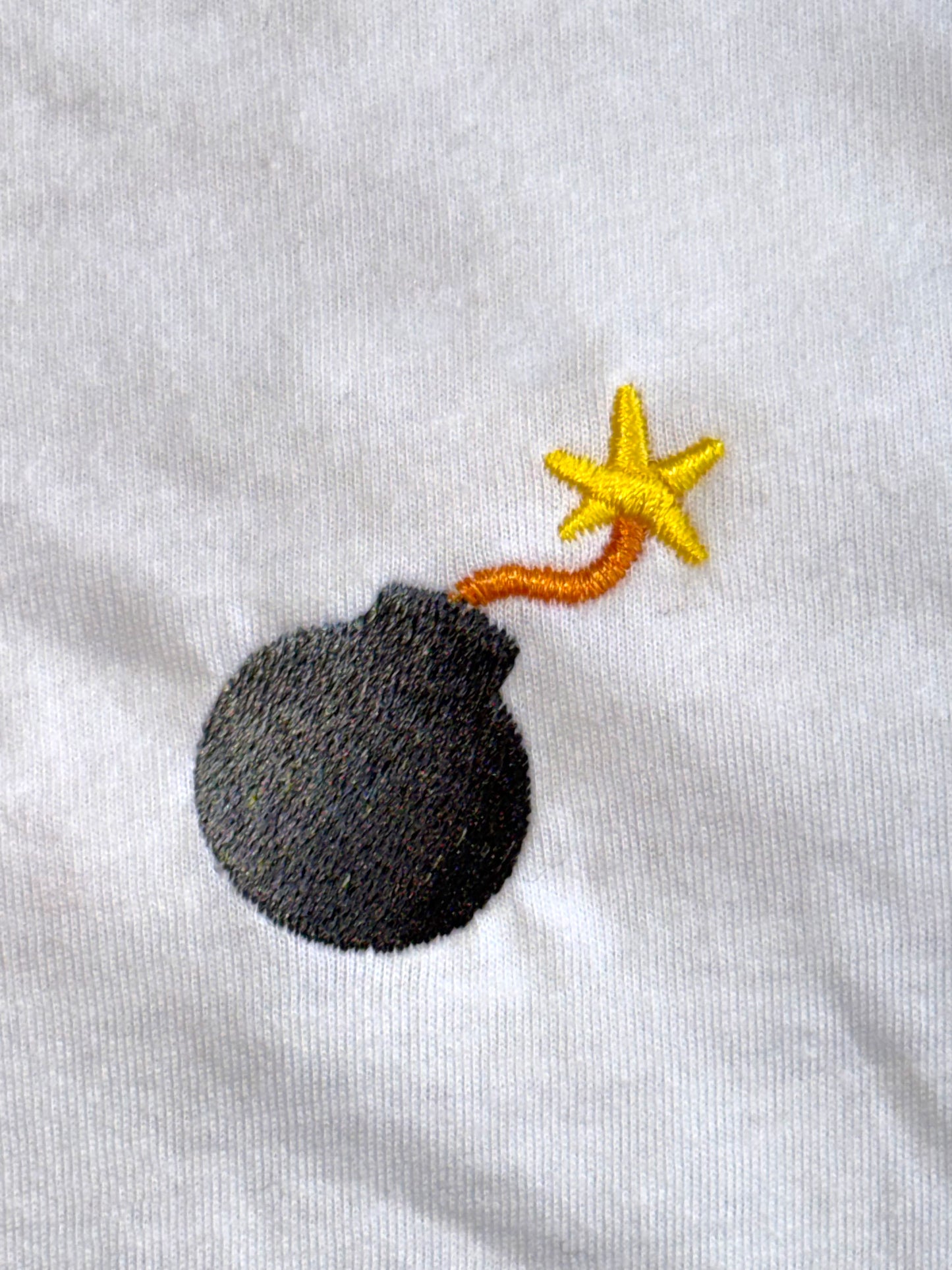 Embroidered design of a bomb with a star on a white background