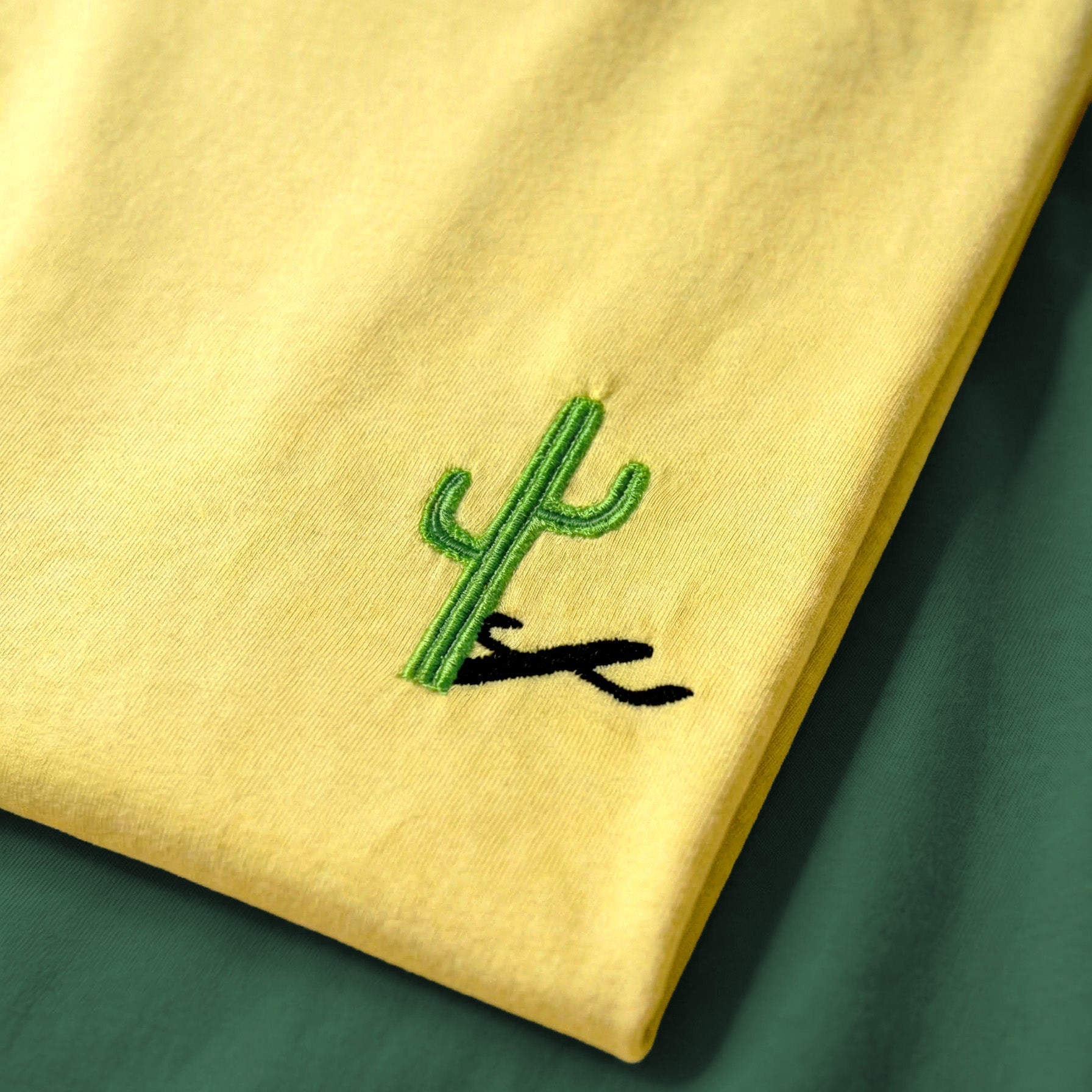 Yellow shirt with a green cactus design on a green background