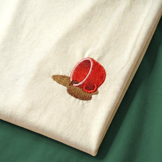 White fabric with a red embroidered flower on a green surface