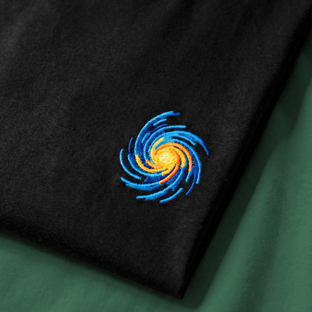 Black fabric with a blue and yellow embroidered design on a green background