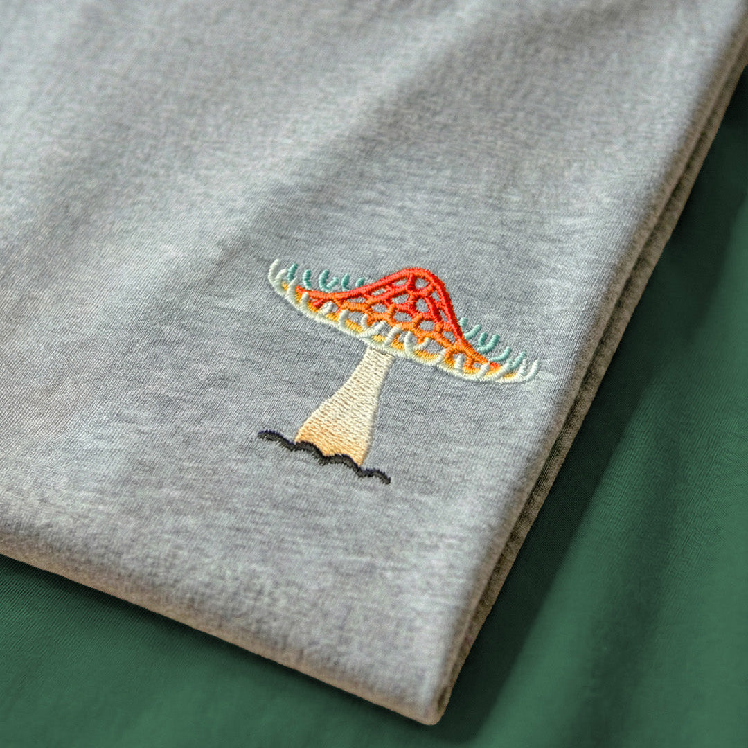 Gray sweatshirt with colorful embroidered design on a green surface