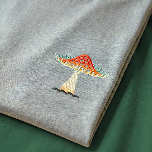 Gray sweatshirt with colorful embroidered design on a green surface