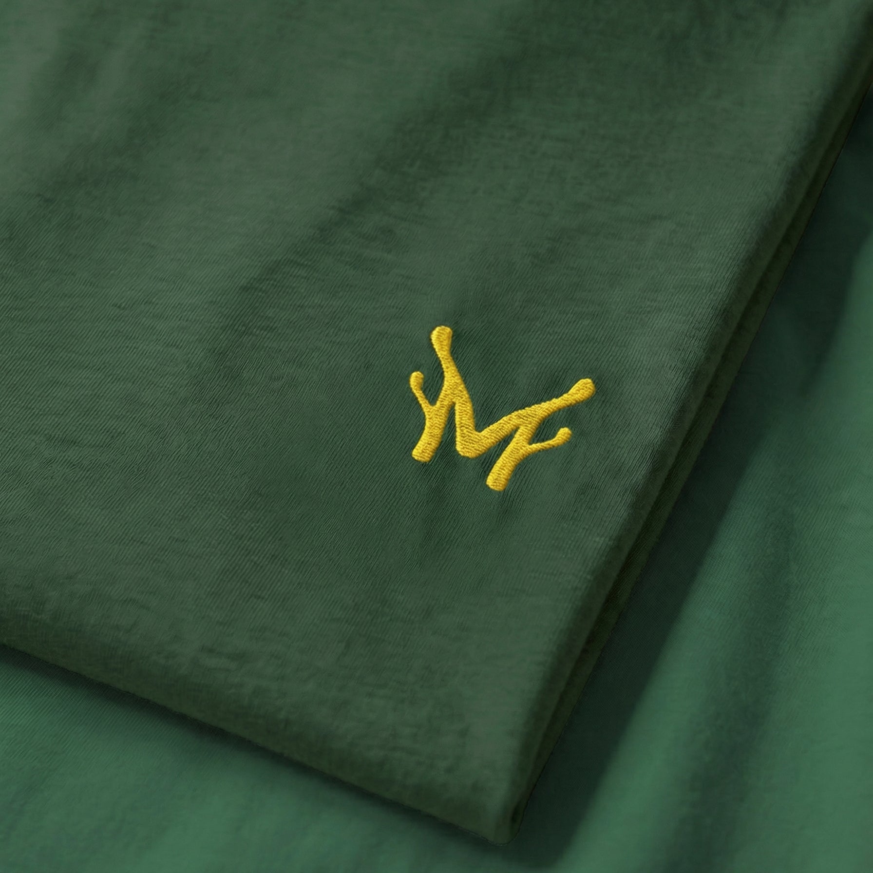 Green fabric with a yellow embroidered design on a matching green background