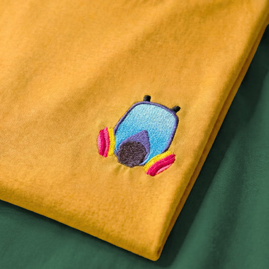 Embroidered colorful respirator design on a mustard yellow fabric background
