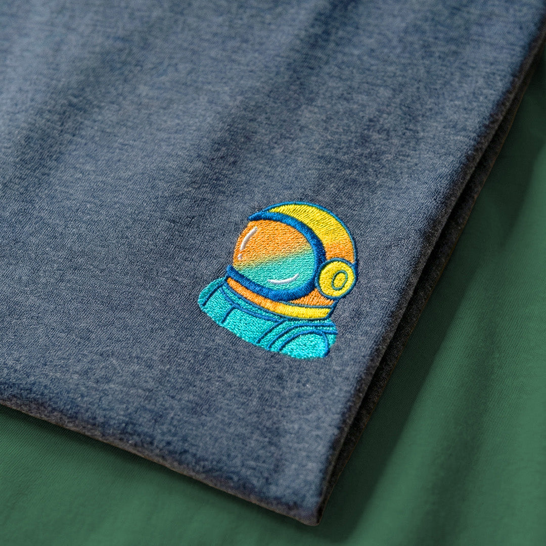 Embroidered design space man on a blue fabric with a green background