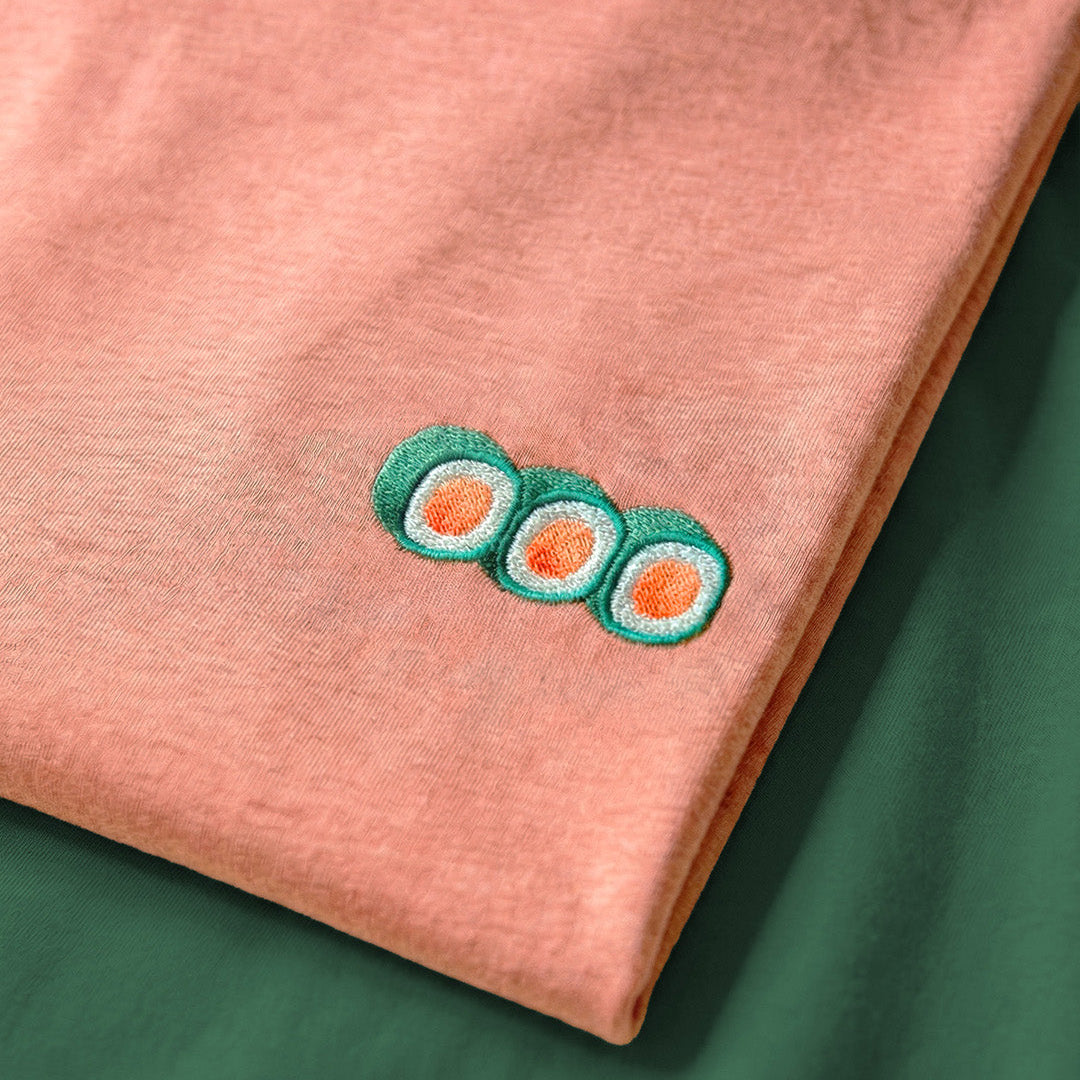 Pink fabric with embroidered sushi design on a green background