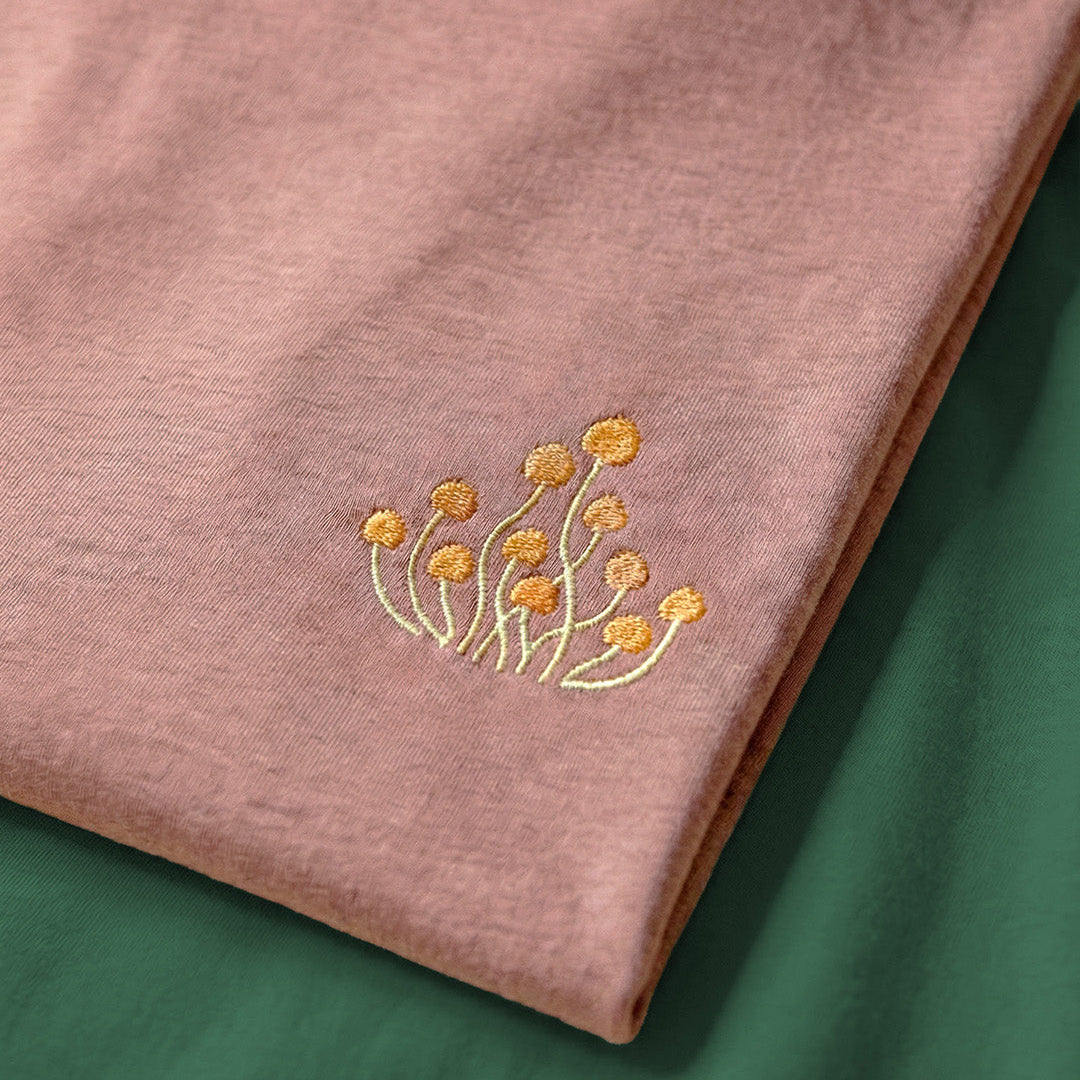Pink fabric with gold floral embroidery on a green background