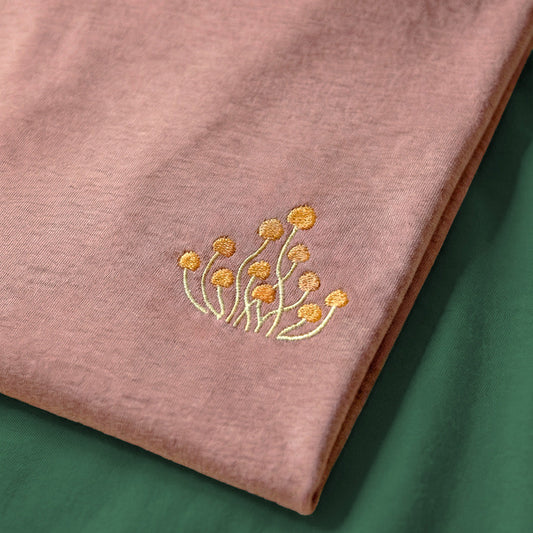 Pink fabric with gold floral embroidery on a green background