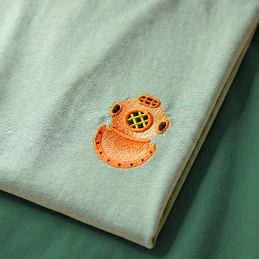 Light gray sweatshirt with an orange embroidered design on a green surface