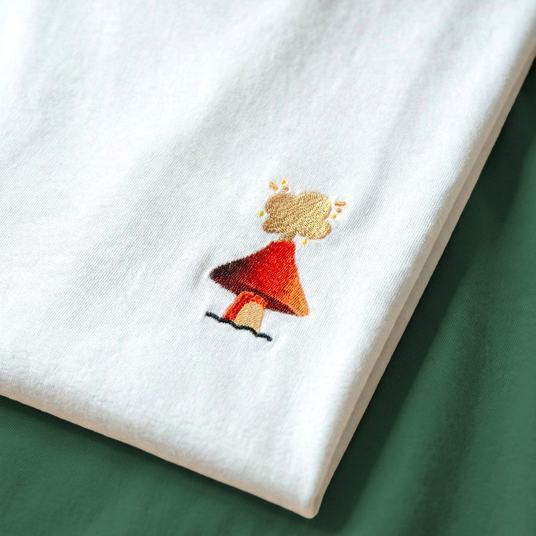 Embroidered design of a mushroom volcano  on a white fabric background