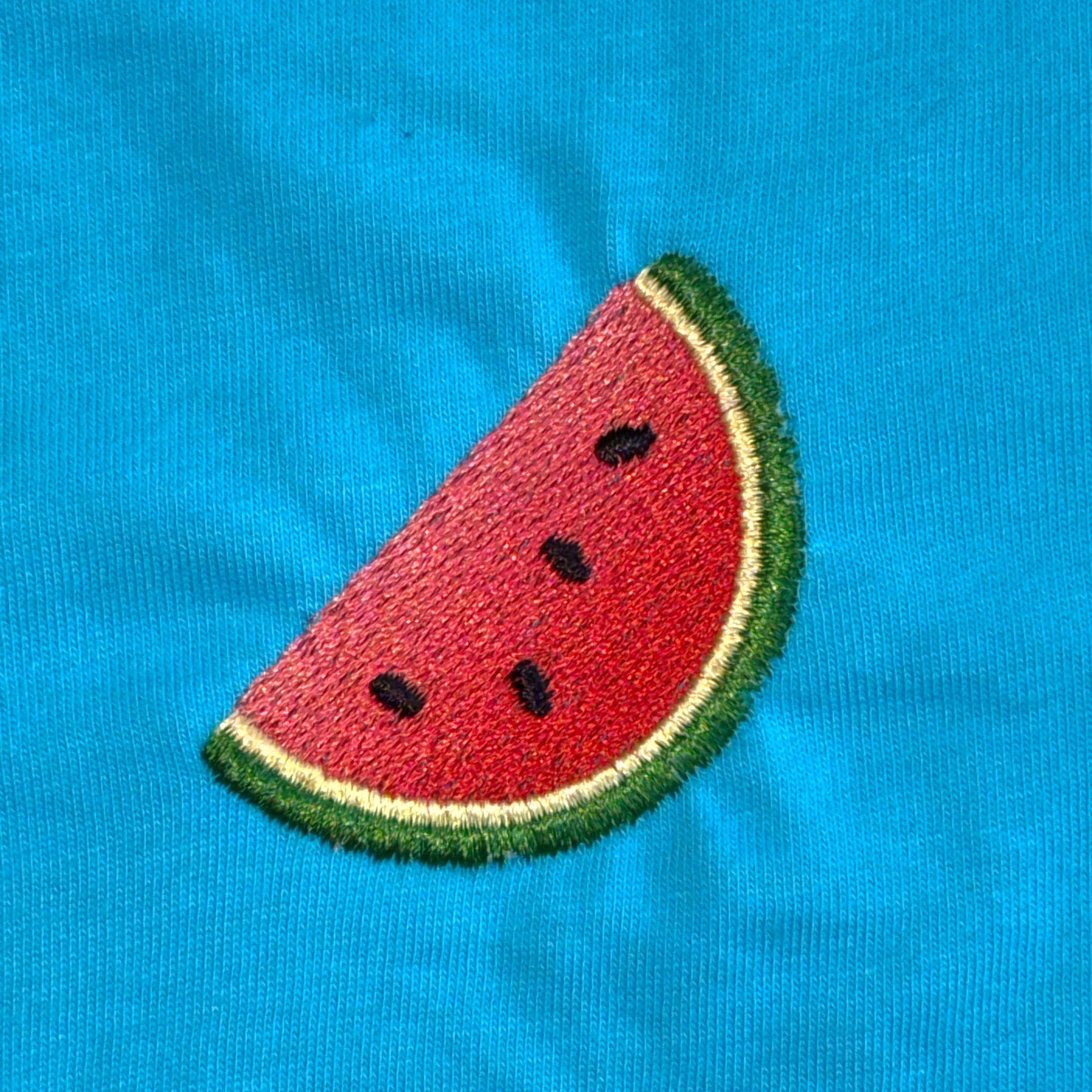 Embroidered watermelon slice on a blue fabric background