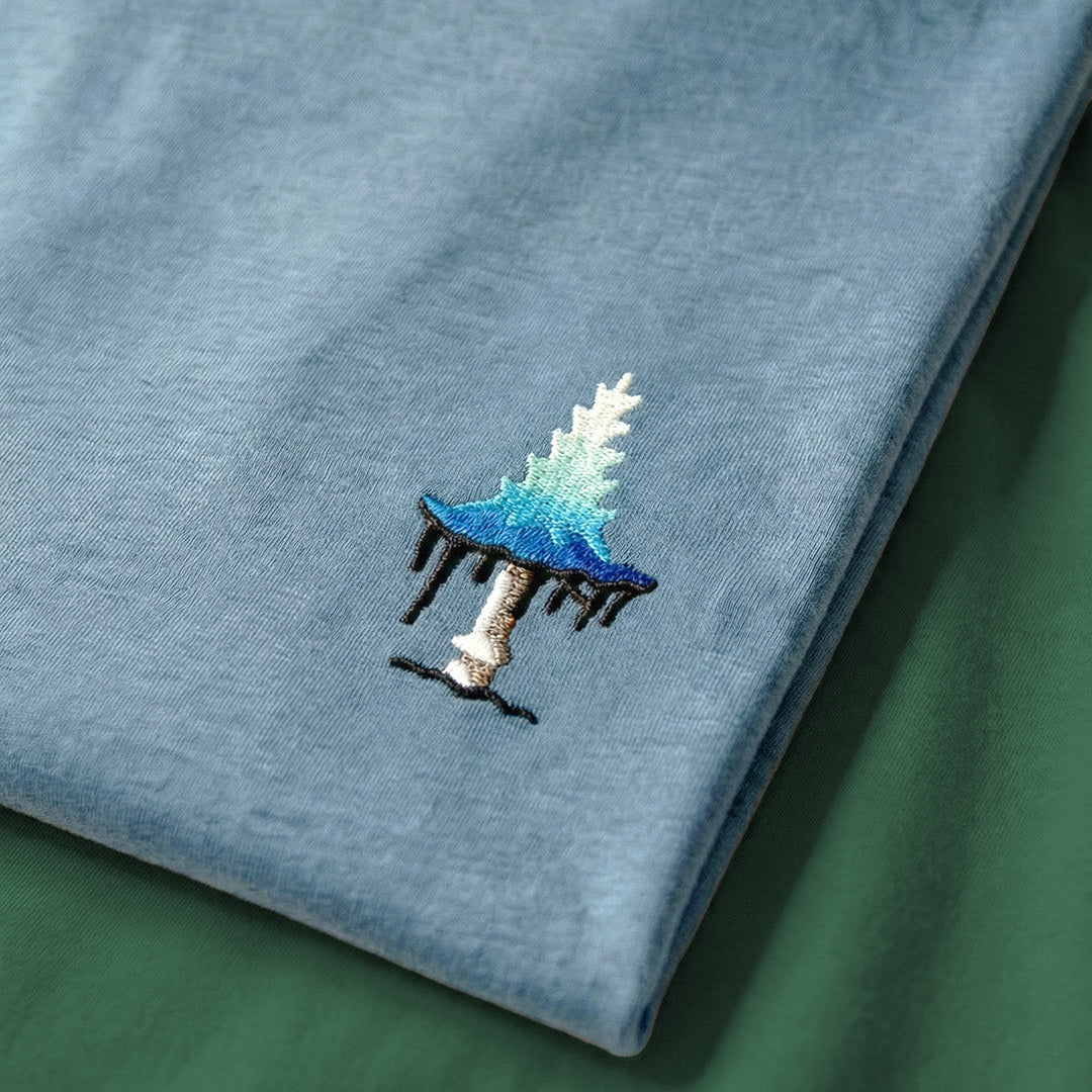 Embroidered design of a blue mushroom on a light blue fabric background